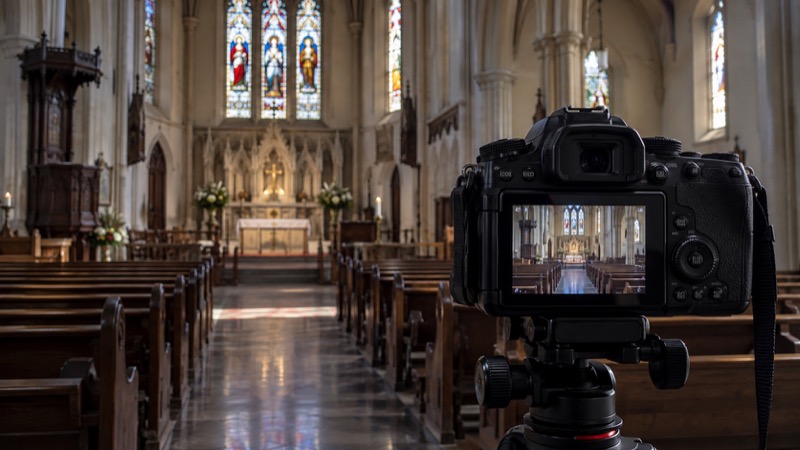 Camera aimed into empty church interior, its monitor shows same empty space.